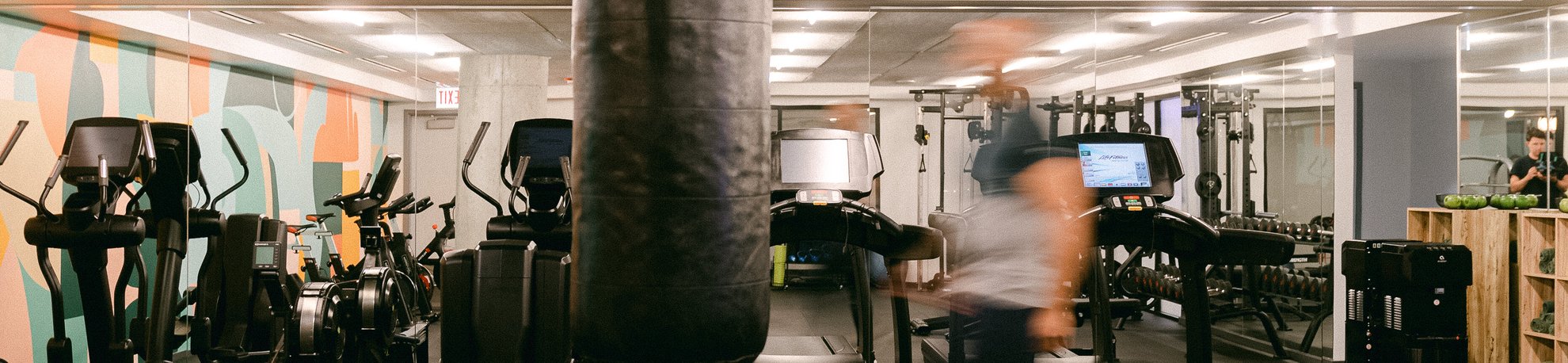 a man walking in the gym with punching bag and different exercise machine at the emily hotel fitness center