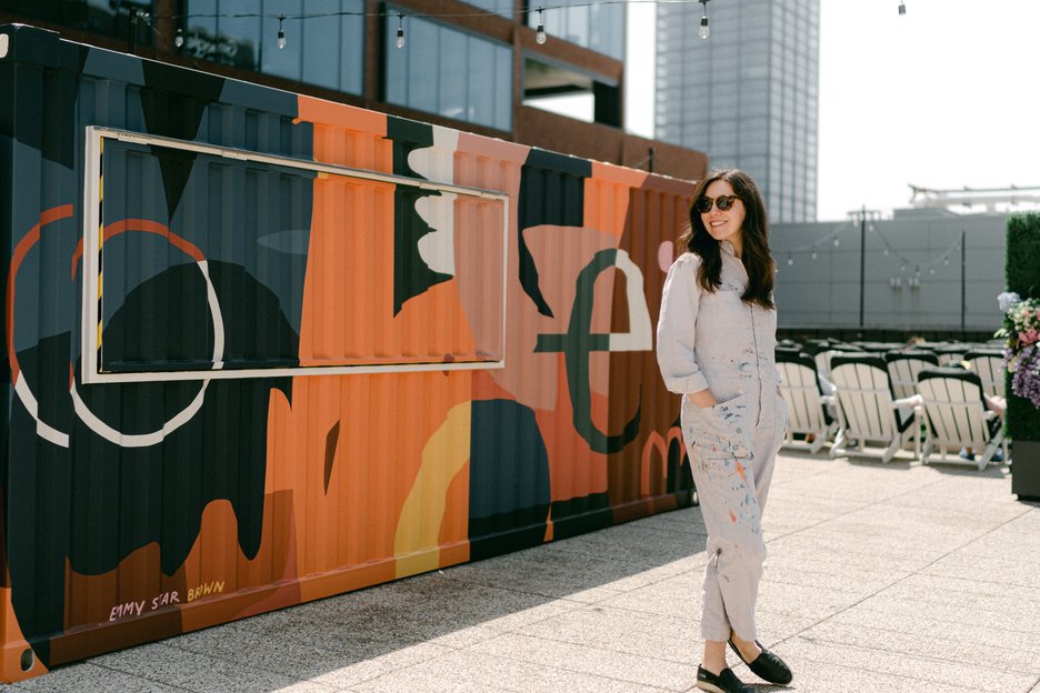 Emmy Star Brown standing in front of the shipping container she painted for the rooftop of The Emily Hotel