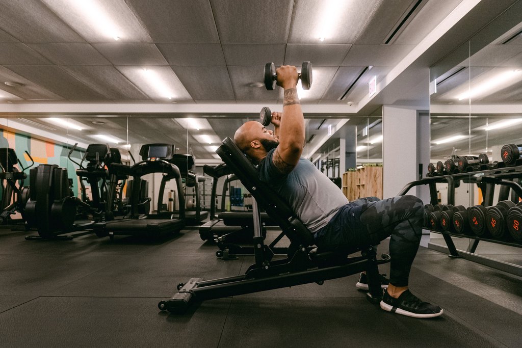 a man performing a bench press exercise at a the emily hotel gym, focusing on his upper body fulton market