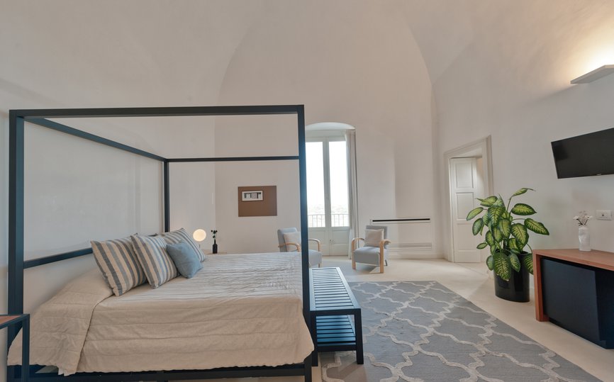 spacious bedroom with king bed and two lounge chairs in deluxe superior room at villa torre bianca by emily hotels