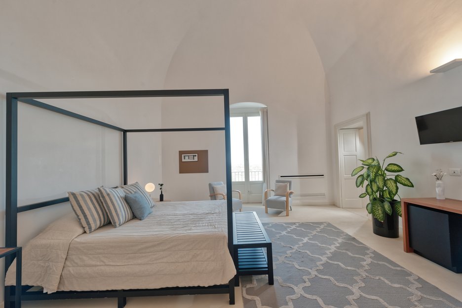 spacious bedroom with king bed and two lounge chairs in deluxe superior room at villa torre bianca by emily hotels