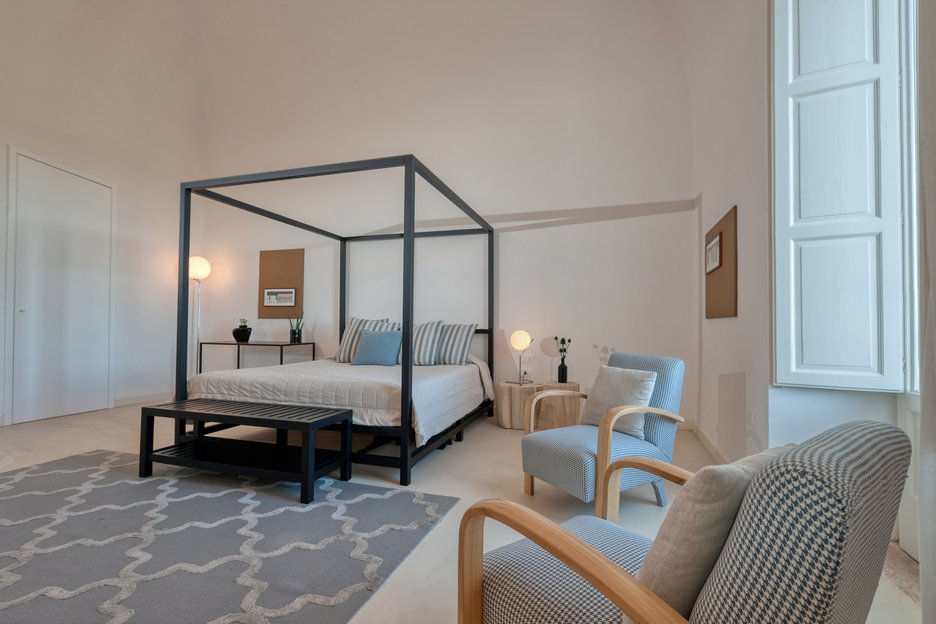 king bed with two chairs in deluxe superior room at villa torre bianca by emily hotels in puglia region of italy