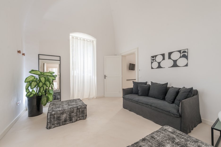 spacious living area with grey couch in rosa junior suite at villa torre bianca by emily hotels