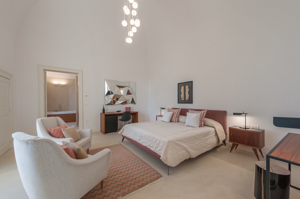 king bedroom with two lounge chairs and work desk in rosa junior suite at Villa Torre Bianca in Puglia Italy
