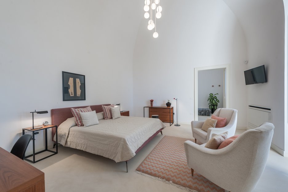 modern bedroom with king bed, work desk, lounge chairs and make up desk in rosa junior suite at villa torre bianca by emily hotels