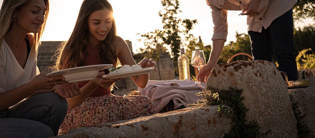 Three people having a picnic at a winery in Puglia close to Villa Torre Bianca