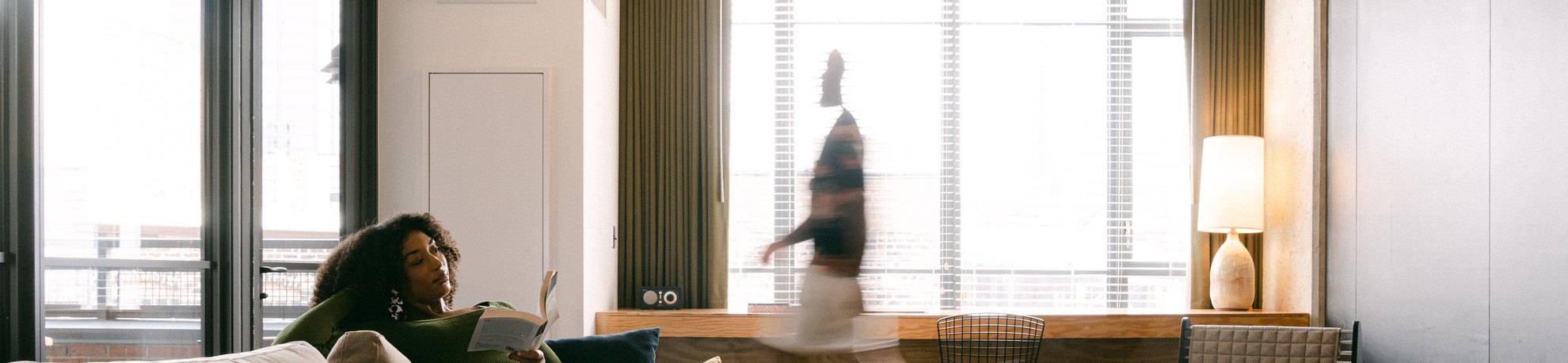 a girl reading a book in a large modern living room of the emily hotel suite with a man walking around in fulton market chicago