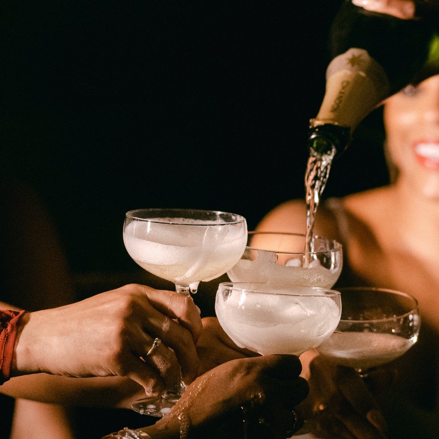 a woman pouring champagne into a glass, creating a sparkling cascade of bubbles and celebration at selva the emily hotel