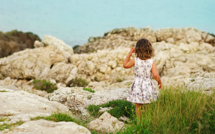 girl in puglia looking at ocean and rocks