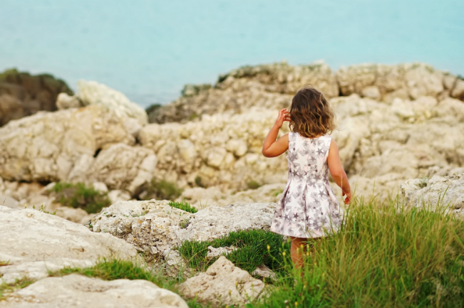 girl in puglia looking at ocean and rocks