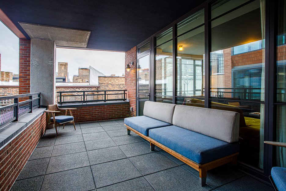 large outdoor balcony with blue couch placed in the center positioned to the city view at the emily hotel chicago fulton market (1)