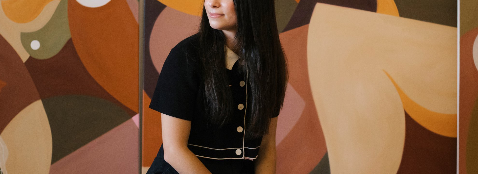 liz sitting on stool in front of paintings