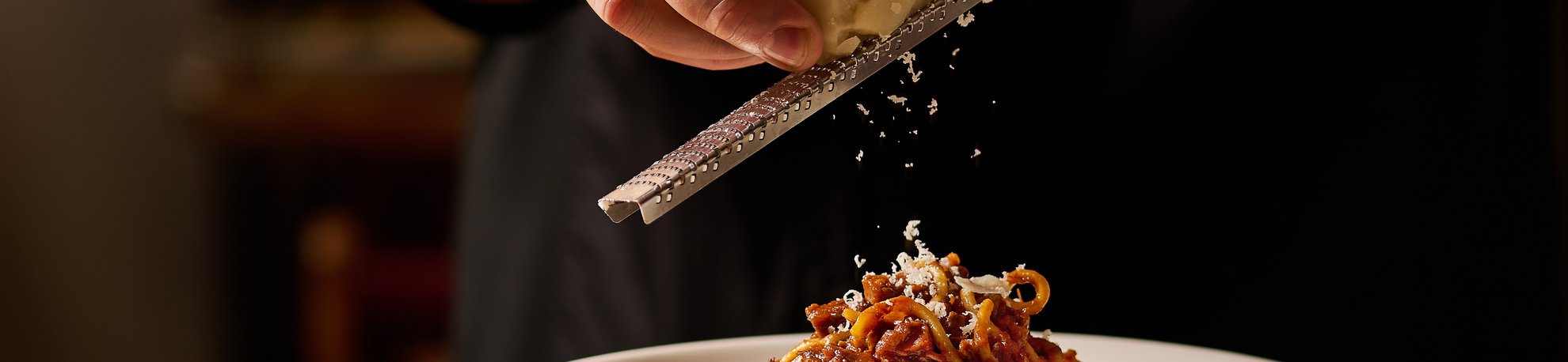 Chef marcello garnishing chittara ragu with cheese