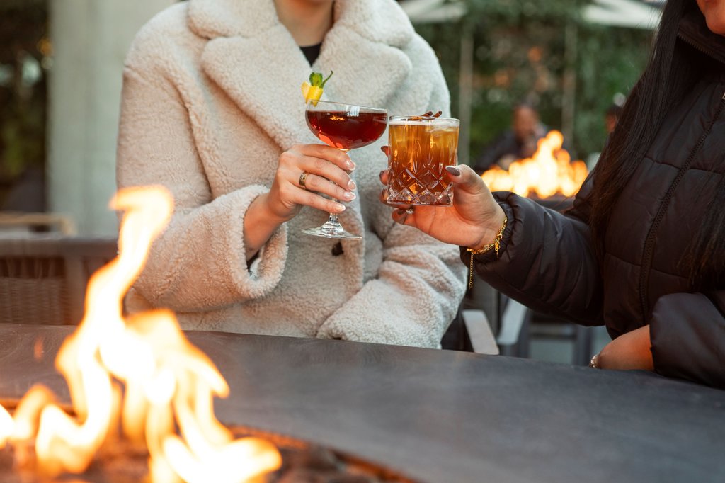 two people having drinks by fire pit located outdoor patio at fora chicago the emily hotel fulton market