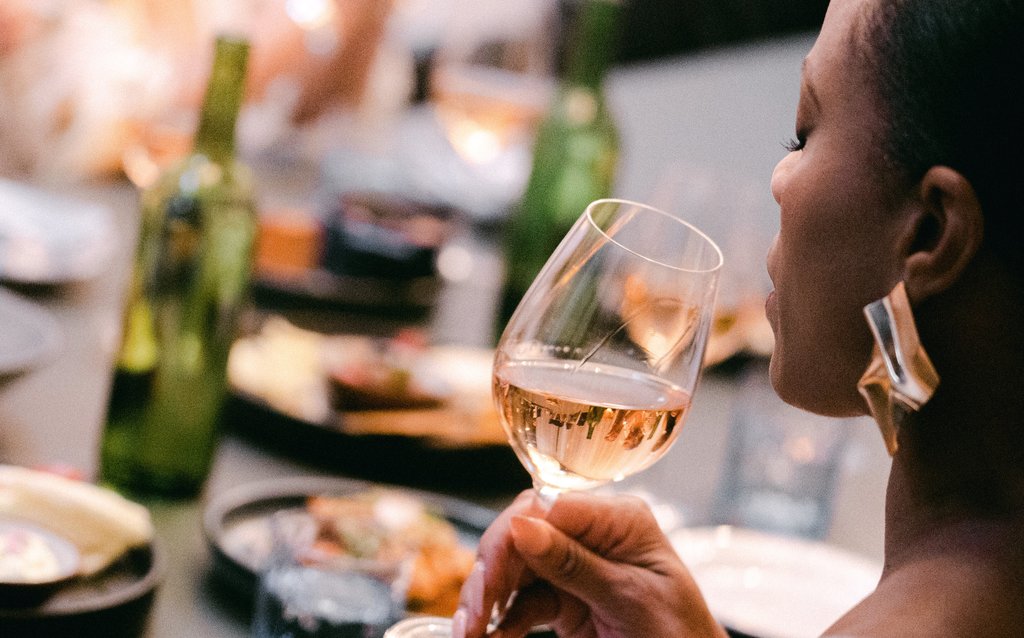 woman bringing wine glass up to her lips while sitting at a private dining table in fora restaurant